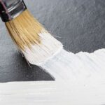draws-a-brush-with-white-paint-on-a-black-background-close-up
